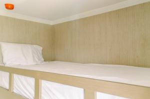 a bed in a room with white sheets and pillows at Simply and Cozy Pool View 2BR at Great Western Apartment By Travelio in Pumpangsineng +11 photos