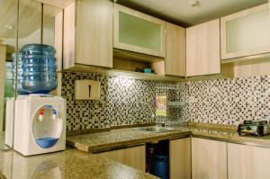 a kitchen with a refrigerator and a sink at Simply and Cozy Pool View 2BR at Great Western Apartment By Travelio in Pumpangsineng