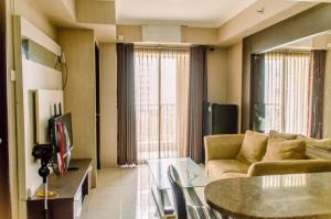 a living room with a couch and a table at Simply and Cozy Pool View 2BR at Great Western Apartment By Travelio in Pumpangsineng