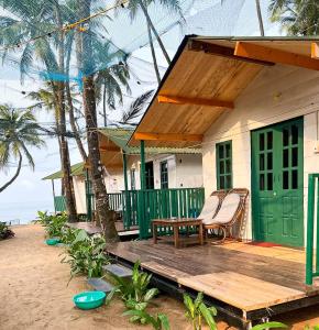 una casa sulla spiaggia con una panchina sotto il portico di The Nest Palolem a Canacona