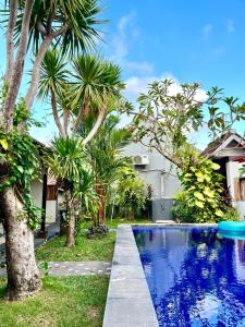 a swimming pool in front of a house with palm trees at Pererenan nengah guest house canggu in Canggu