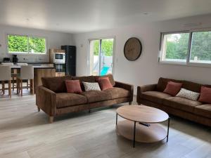 a living room with two couches and a table at Le Petit Chemin in Sainte-Mère-Église