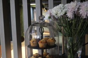 a glass display with muffins and a vase of flowers at Plaza Hotel, Chorley, Sure Collection By BW in Chorley