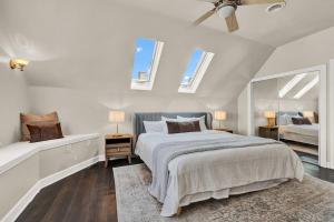 a white bedroom with a bed and two windows at NEW! Fun & style Eastside MKE Best Day Townhouse in Milwaukee
