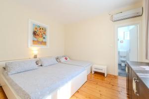 a white bedroom with a bed and a kitchen at Family friendly seaside apartments Iz, Iz - 22025 in Veli Iž