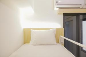 a bed with a white pillow in a room at Fully Furnished with Pleasure 2BR at Sky House BSD Apartment By Travelio in Tangerang +19 photos