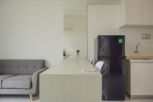 a kitchen with a counter with a refrigerator and a couch at Fully Furnished with Pleasure 2BR at Sky House BSD Apartment By Travelio in Tangerang