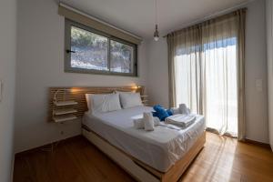 a bedroom with a bed with white sheets and a window at Cella Villa in Kalamata