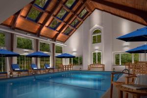 a swimming pool with chairs and blue umbrellas at Inn on the Square in Falmouth