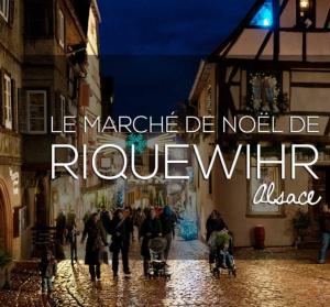 a group of people walking down a street at night at Le petit Riquewihr in Riquewihr