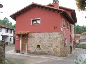 ein rotes Haus mit einer Steinmauer in der Unterkunft Casas Rurales La Casina in Intriago