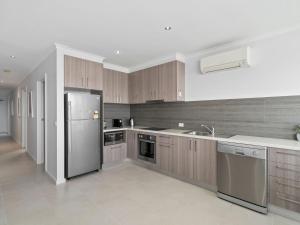 a kitchen with wooden cabinets and a stainless steel refrigerator at Yarrawonga Lakeside Apartment 50 in Mulwala