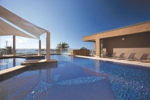 Una piscina con sillas y un edificio. en Rydges Hotel Port Macquarie, en Port Macquarie
