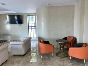 een woonkamer met banken en stoelen en een televisie bij Speranza Hotel Entebbe in Entebbe