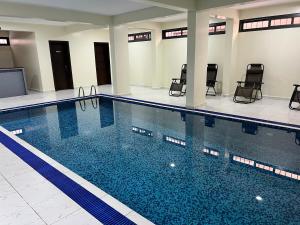een groot zwembad met stoelen in een gebouw bij Speranza Hotel Entebbe in Entebbe