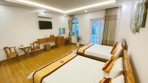 a hotel room with two beds and a desk at Hùng Thi Hotel in Cái Răng
