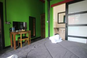 a bedroom with green walls and a bed and a desk at Bat Chum Villa in Phnom Penh