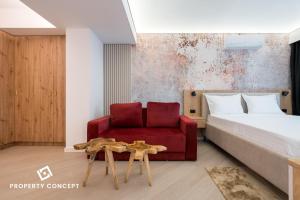 a bedroom with a bed and a red chair at Cortina Concept Studio 128 in Voluntari