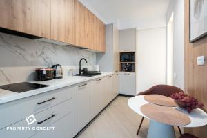 a kitchen with white cabinets and a table and a sink at Cortina Concept Studio 128 in Voluntari