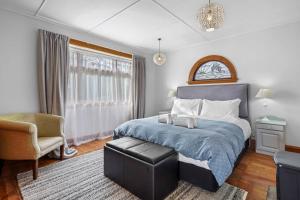 a bedroom with a bed and a chair and a window at Morgan's Treasure in Hanmer Springs