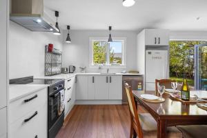a kitchen with white cabinets and a table and a dining room at Morgan's Treasure in Hanmer Springs