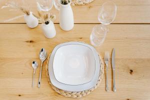 a table with a plate and cutlery on it at Küsten Suite Grachten Suite 2 direkte Wasserlage, Terrasse, 76qm, Neubaugebiet in Greetsiel