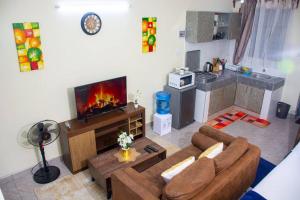 a living room with a couch and a tv at Derosa Studio Fig Tree Apartment in Kilifi