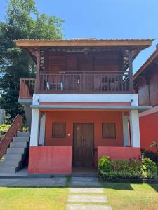 a red house with a balcony on top of it at Pecatu home stay in Uluwatu +2 photos