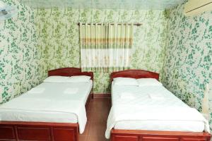 2 camas en una habitación con papel pintado verde y blanco en Thanh Nhàn 1 Hotel Cà Mau - by BAYLUXURY, en Xóm Lơn