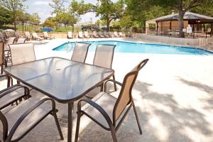a glass table and chairs next to a swimming pool at Holiday Inn Austin Midtown by IHG in Austin