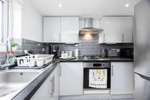 a kitchen with white cabinets and a stove top oven at Quick Access to London City, Self Check-in! in London