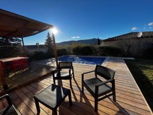 Dos sillas y una mesa en una terraza de madera. en Villa Jungle house, en Alba-la-Romaine