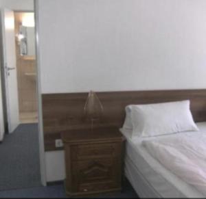 Un dormitorio con una cama y una mesita de noche con una lámpara. en Agency CSA Nürnberg, en Núremberg