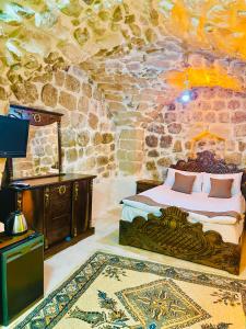 une chambre avec un lit dans une pièce en pierre dans l'établissement ŞEHRAZAD OTEL MERDİN masal şehri konağı, à Mardin