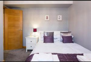 a bedroom with a large white bed with purple pillows at The Light Villa House Entire luxury 3 bedrooms in Killingbeck