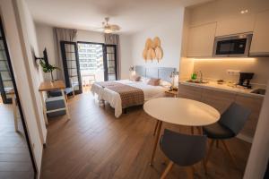a bedroom with a bed and a table and a kitchen at Los Cardones Boutique Village in Playa de las Americas