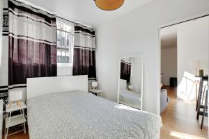 a white bedroom with a bed and a mirror at Centre Vincennes - Logement cosy in Vincennes