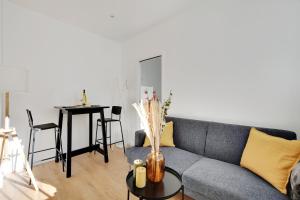 a living room with a couch and a table at Centre Vincennes - Logement cosy in Vincennes +2 photos