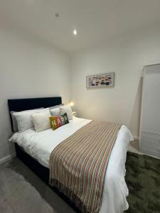 a bedroom with a large bed with a striped blanket at Modern apartment with sea views in Portrush