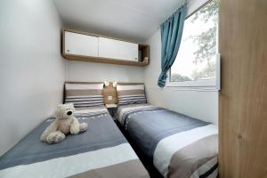 a small bedroom with two beds and a teddy bear at Albatross Mobile Homes on Camping Bijela Uvala in Poreč