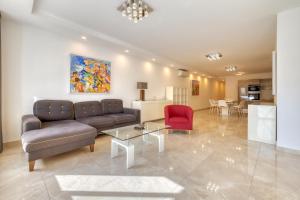 a living room with a couch and a red chair at St Georges Bay Oasis Steps from the Beach in St. Julianʼs