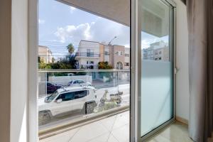 a window with a view of a car on a street at St Georges Bay Oasis Steps from the Beach in St. Julianʼs +54 photos