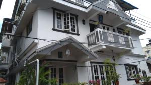 a white house with black windows at Gloria Homestay in Cochin