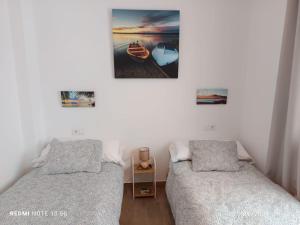 Un dormitorio con dos camas y un cuadro en la pared. en Tierra y Mar, en Sanlúcar de Barrameda