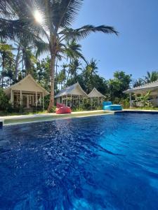 a pool at a resort with palm trees at The Palms Penida in Nusa Penida