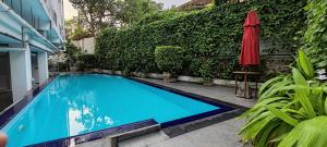 a swimming pool with a red umbrella next to a building at Jays Apartment Colombo 05 in Colombo