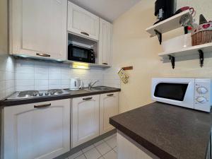 eine Küche mit weißen Schränken und einer weißen Mikrowelle in der Unterkunft Résidence Atrey 403 Clés Blanches Courchevel in Courchevel + 6 Fotos