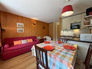 ein Wohnzimmer mit einem Tisch und einer roten Couch in der Unterkunft Résidence Atrey 403 Clés Blanches Courchevel in Courchevel