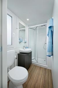 a white bathroom with a toilet and a sink at Albatross Mobile Homes on Camping Laguna Village in Porto Falconera