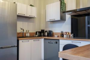 a kitchen with white cabinets and a wooden table at La Cour du Cygne - By PrestiPlace in Tours